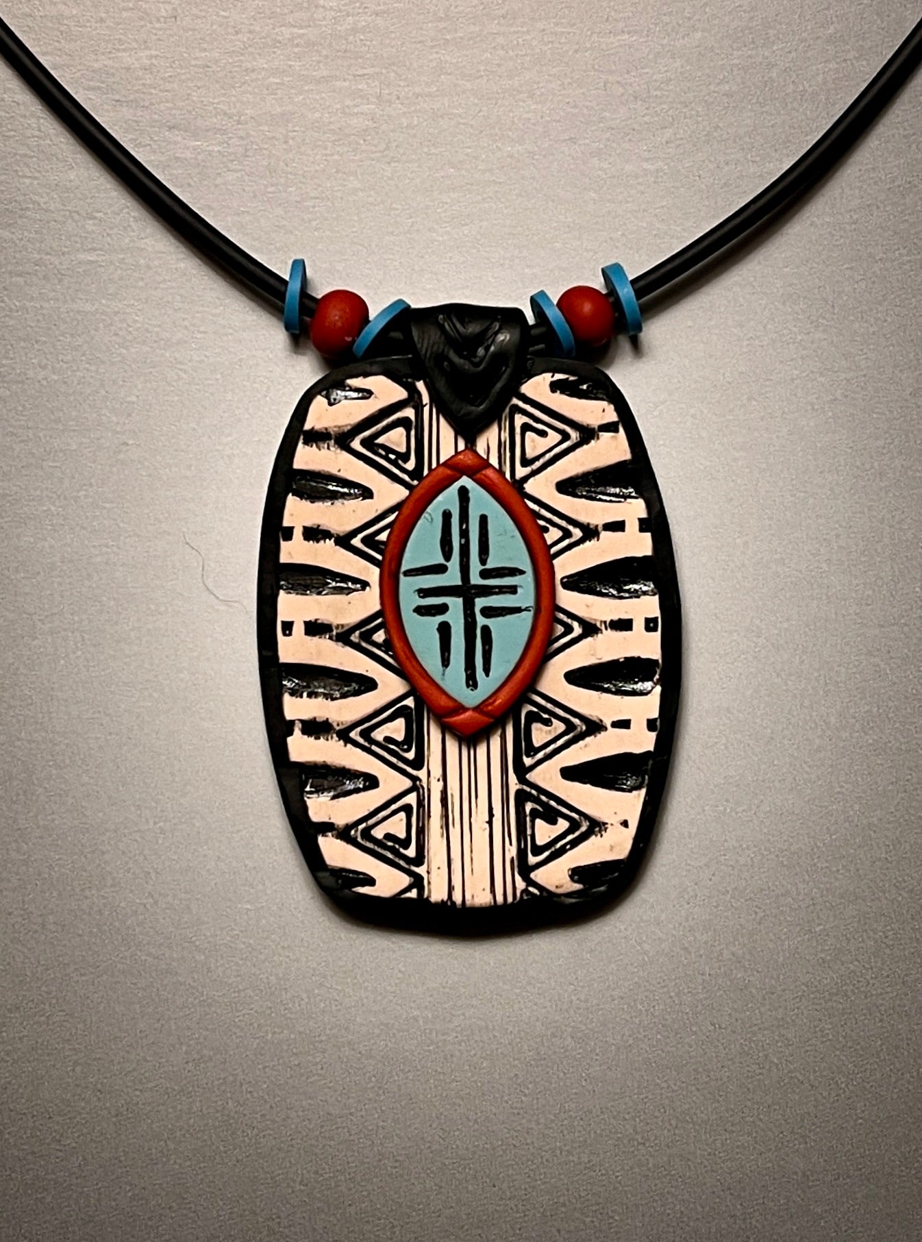 Beautiful, distinctive tribal textured, and layered polymer clay pendant. Black and white with turquoise and rust accents.