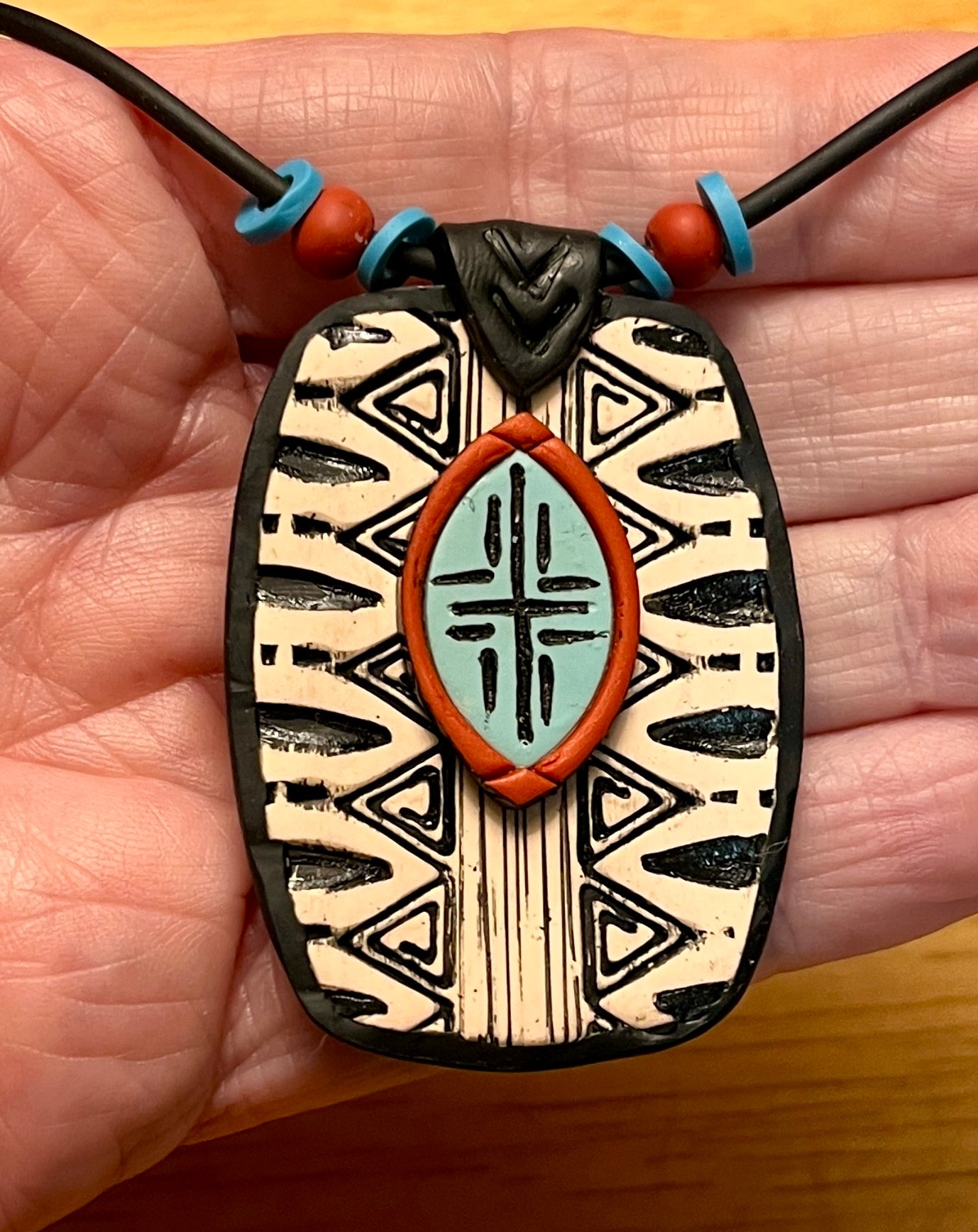 Beautiful, distinctive tribal textured, and layered polymer clay pendant. Black and white with turquoise and rust accents.